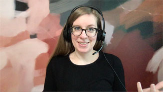 Smiling woman with headset and glasses in front of a multicolor background